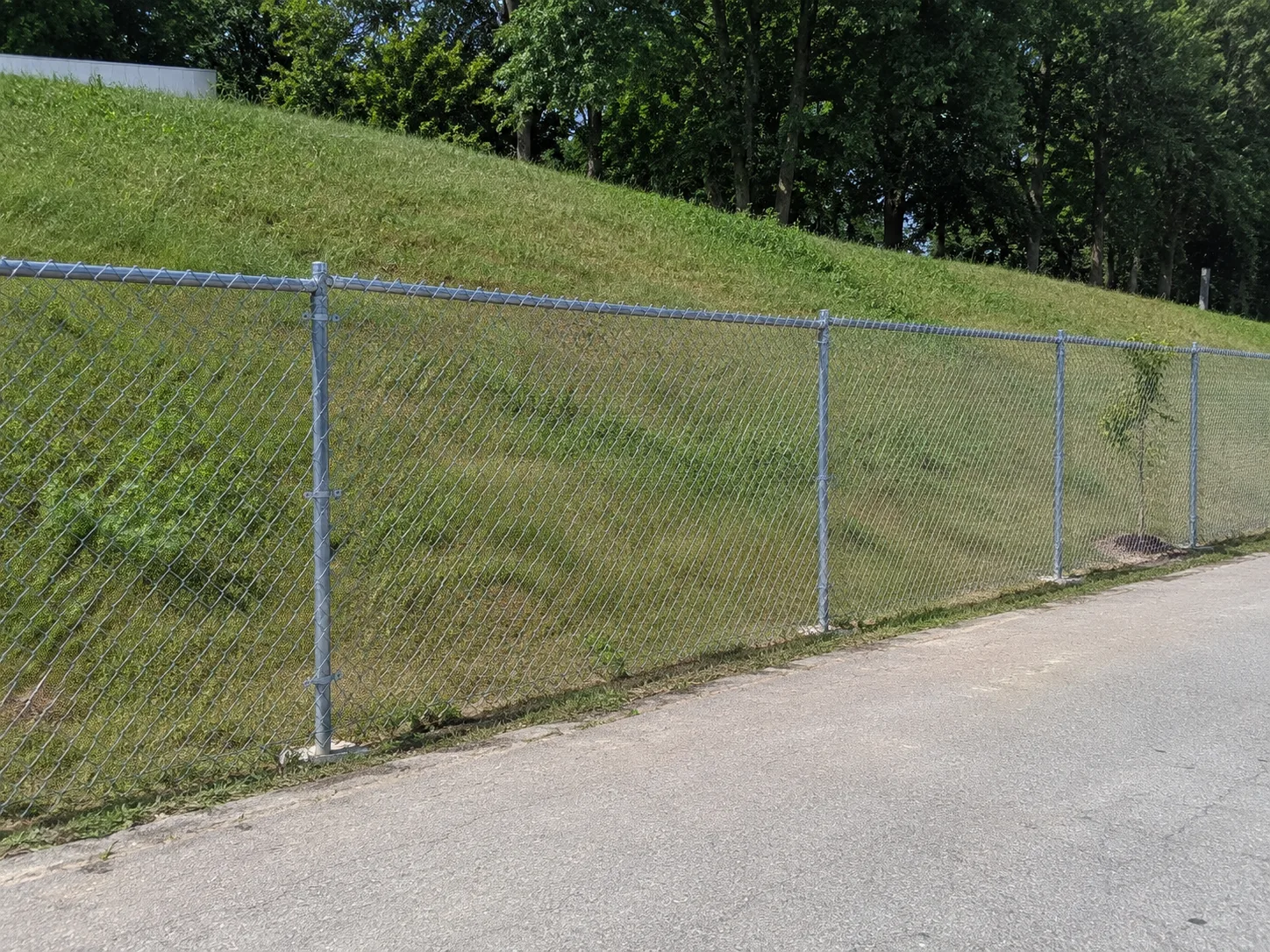 Galvanised chain-link fence crossing an open grassy slope